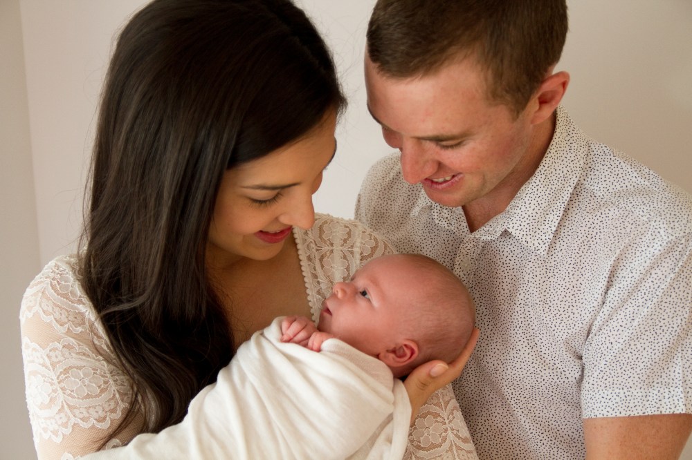 Parents posing with newborn baby during studio photography session,