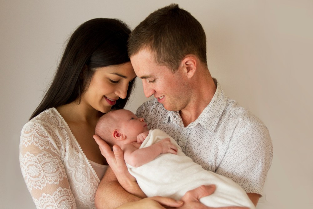 Parents posing with newborn baby during studio photography session,