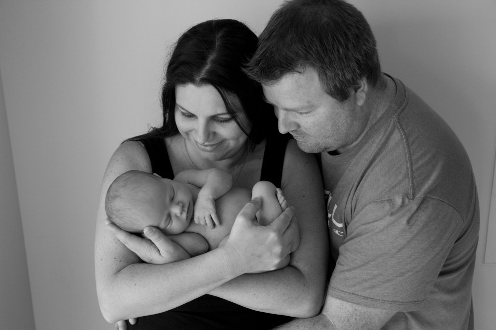 Mum and dad with newborn baby. Parents posing with newborn.